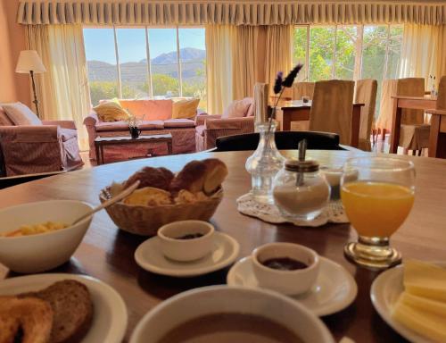a table with a breakfast of bread and orange juice at Hostería La Viña in La Cumbre