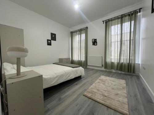 a white bedroom with a bed and a rug at London rooms in London