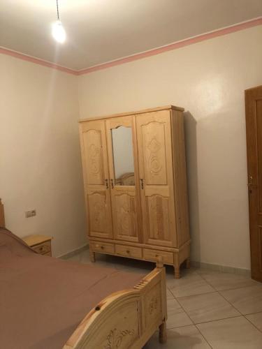 a bedroom with a bed and a wooden cabinet at Residence al Rahma 03 in Monte ʼArrouit