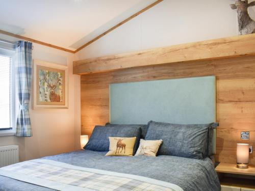 sypialnia z łóżkiem z niebieskim zagłówkiem w obiekcie Beaumont Lodge w mieście Plumbland