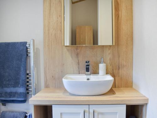 a bathroom with a white sink and a mirror at Beaumont Lodge in Plumbland