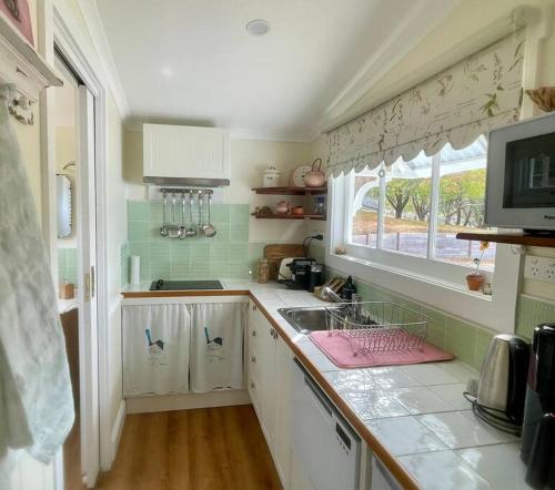 una pequeña cocina con fregadero y ventana en Maple Hill Cottage, en Castle Forbes Bay