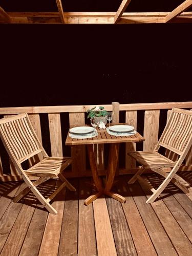 a wooden table and two chairs on a wooden deck at Gîte et Roulotte dans les Vosges in Remiremont