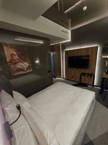 a bedroom with a white bed and a flat screen tv at Hotel Vojvoda Putnik in Vranje