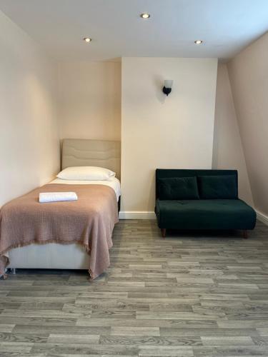 a bedroom with a bed and a green couch at The Lily Aparts in London