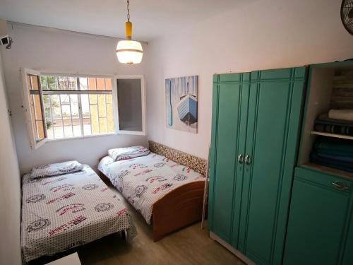 ラスパルマス・デ・グランカナリアにあるCasa Tinkoのベッド2台と緑のキャビネットが備わる客室です。