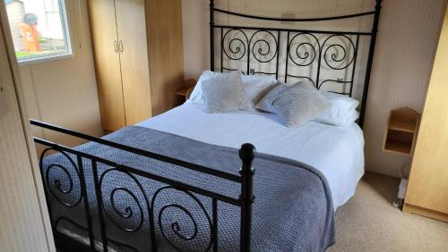 a bedroom with a black bed with white sheets and pillows at Caravan near Port Carlisle in Aikton