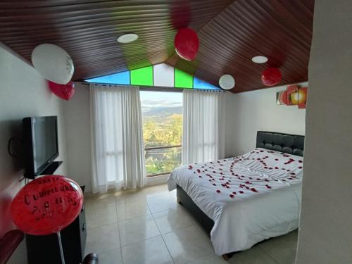 um quarto com uma cama e uma grande janela em Altovento Sutamarchán em Sutamarchán