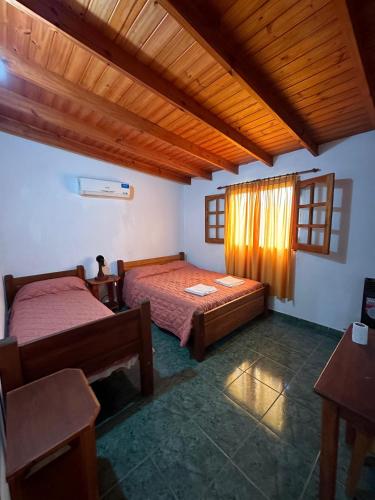 1 dormitorio con 2 camas y techo de madera en El Roble en Merlo