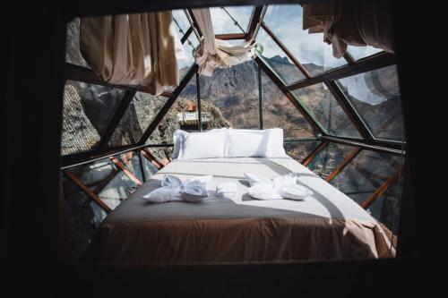 Habitación con cama en una torre de cristal en Vertical Sky Luxury Suites, en Ollantaytambo