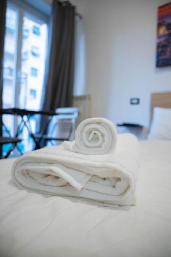 a stack of white towels sitting on a bed at Genova Suite in Genova