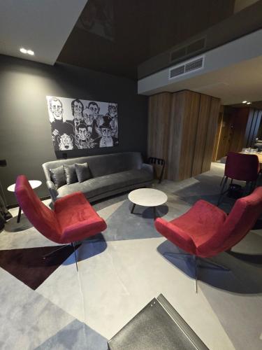 a living room with red chairs and a couch at Hotel Vojvoda Putnik in Vranje