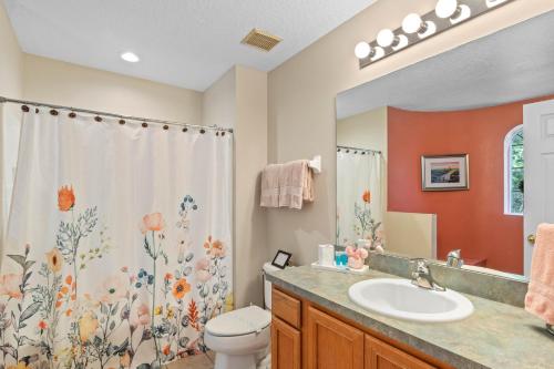 a bathroom with a sink and a toilet and a shower curtain at Be-Our-Guest Home! 15 mins to Disney! in Kissimmee