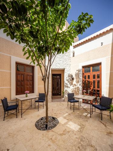 a tree in a courtyard with chairs and tables at Casa Tavera- Adults Only in Mérida