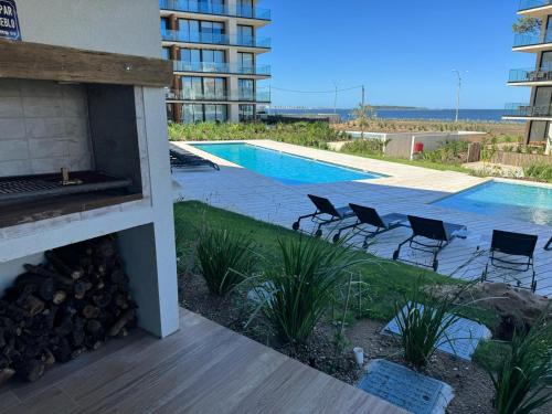 a swimming pool with chairs next to a building at Moderno in Punta del Este