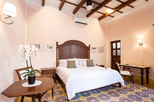 a bedroom with a large white bed and a desk at Casa Tavera- Adults Only in Mérida