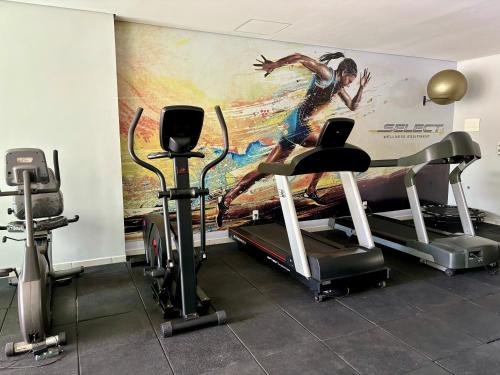 a gym with cardio equipment and a painting on the wall at Ap completo com ar e garagem coberta próximo ao metrô in Brasilia