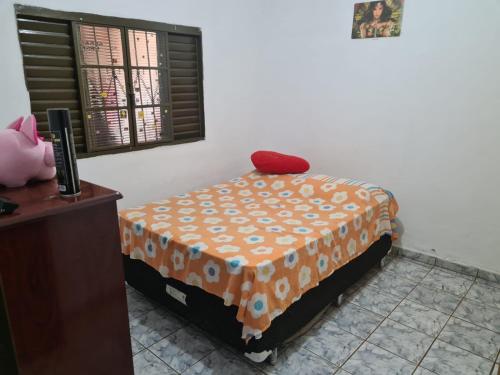 a bedroom with a bed with an orange blanket and a window at Casa para Temporada Agrishow 2024 in Ribeirão Preto