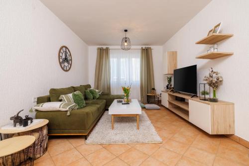a living room with a green couch and a tv at Apartmani Anđelić- Fužine 1 in Fužine