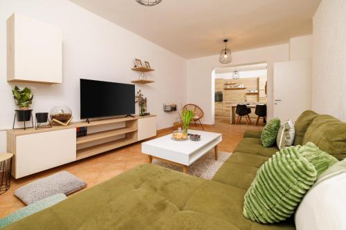 a living room with a green couch and a flat screen tv at Apartmani Anđelić- Fužine 1 in Fužine