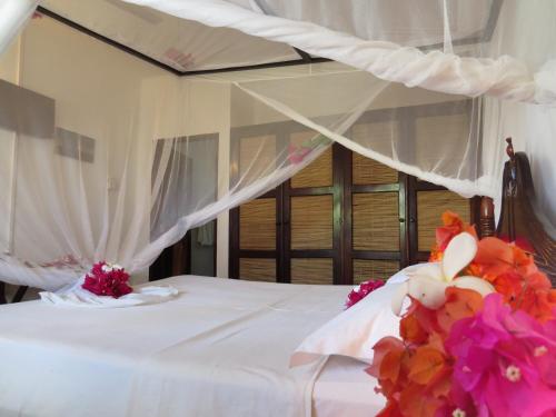 a bedroom with a bed with flowers on it at Karibuni Hotel & Villas in Mambrui