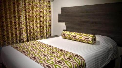 a bed with a headboard and a pillow on it at Jewel City Inn in Glendale