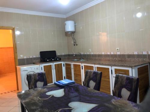 a kitchen with a table with chairs and a counter top at Residence al Rahma 02 in Monte ʼArrouit