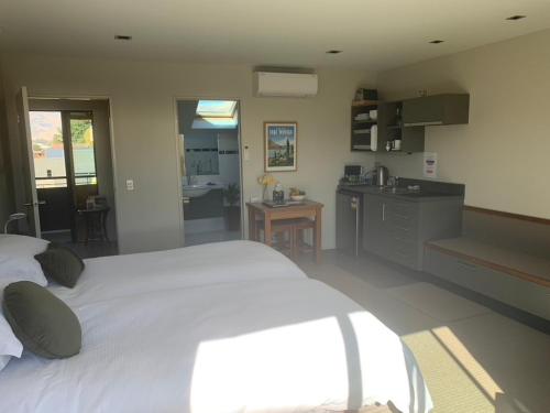 a bedroom with a large white bed and a kitchen at Aspiringlofts in Wanaka