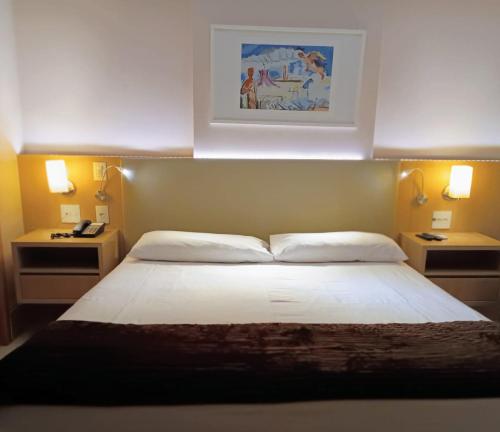 um quarto com uma grande cama branca e 2 luzes em Flat sem café da manhã - Cullinan (SHN Brasília) em Brasília