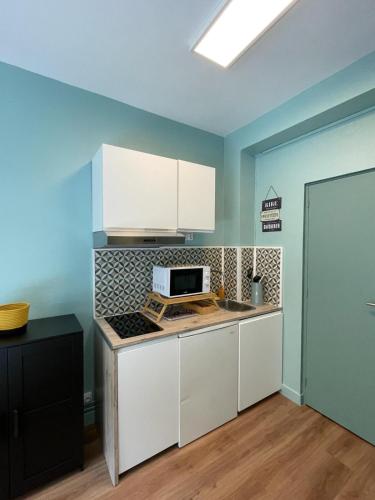 une cuisine avec des armoires blanches et un four à plaques de cuisson dans l'établissement Cozy studio Metz, à Metz