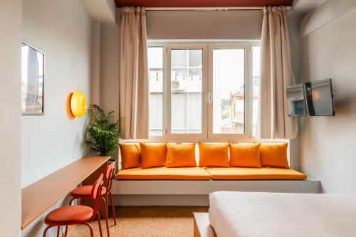 - un siège de fenêtre dans une chambre d'hôtel avec des oreillers orange dans l'établissement Acre Urban Studios in Monastiraki, à Athènes