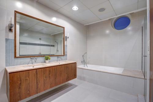 a bathroom with a tub and a large mirror at Oceana Atlantic Seaside Apt in Dubai