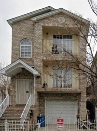 a brick house with a balcony and a garage at Room G DIVINE VILLA AND RESORT, 6 MINS TO AIRPORT, 4MINS TO PENN STATION. in Newark
