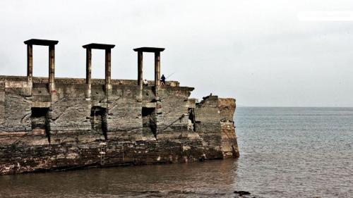 a person standing on top of a pier in the ocean at Hotel Villanueva San Jorge de Heres in Villanueva