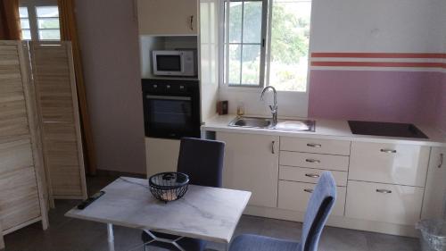 uma cozinha com uma mesa, uma pequena mesa e um lavatório em Location Liliane em Bouillante