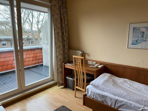 a bedroom with a bed and a desk and a window at Hotel Zum Kaffeekännchen in Norderstedt
