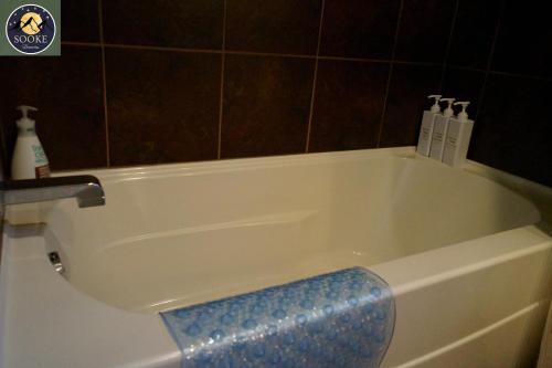 bañera blanca con asiento azul en el baño en SookeDreams, en Sooke