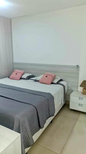 a bedroom with a large bed with pink pillows at CJC Short Stay Natal in Natal