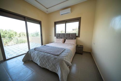 a bedroom with a bed and a large window at villa ourika view on mountain in Sbiti