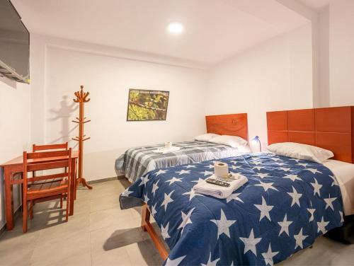 um quarto com uma cama, uma secretária e uma mesa em YURAQ WASI Hotel/Restobar em Huánuco