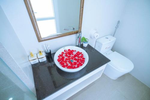 La salle de bains est pourvue d'un lavabo et de fleurs rouges. dans l'établissement Three-bedroom house with sea view, à Hạ Long
