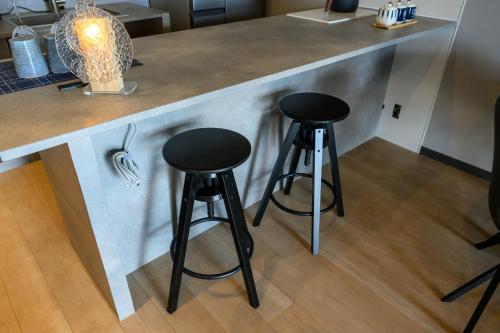 a kitchen with two black stools at a counter at Yiyi Villa Awaji 淡路島西海岸夕日百選のvilla BBQ釣りゴルフ in Awaji