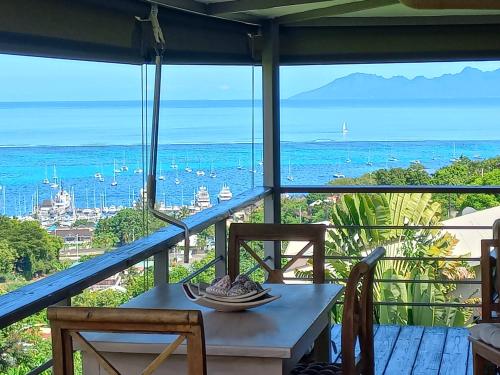a table and chairs on a balcony with a view of the ocean at MARINA BLUE fabuleux Appartement vue LAGON in Punaauia
