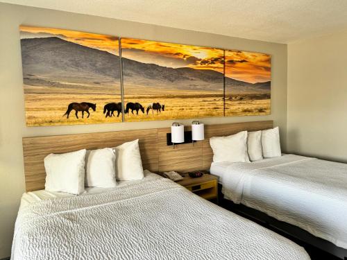 two beds in a hotel room with paintings on the wall at Days Inn by Wyndham Van Horn TX in Van Horn