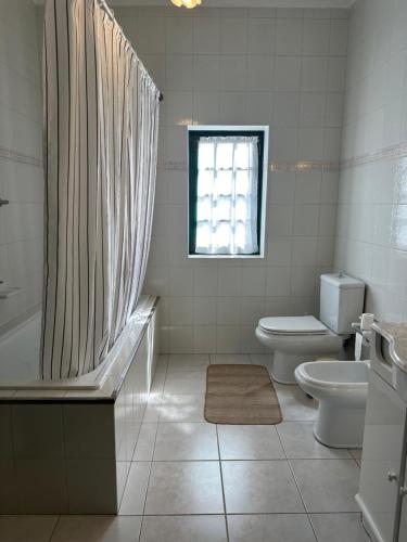 ein Bad mit einer Badewanne, einem WC und einem Fenster in der Unterkunft Casa das Mouras- Rio de Moinhos in Rio de Moinhos
