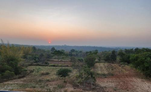 una vista de un campo con una puesta de sol en el fondo en Birds of paradise foundation, en Bangalore