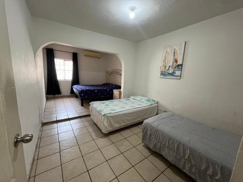 um pequeno quarto com 2 camas e uma cadeira em Casa grande y centrica, 3 cuartos y 2 baños em Hermosillo