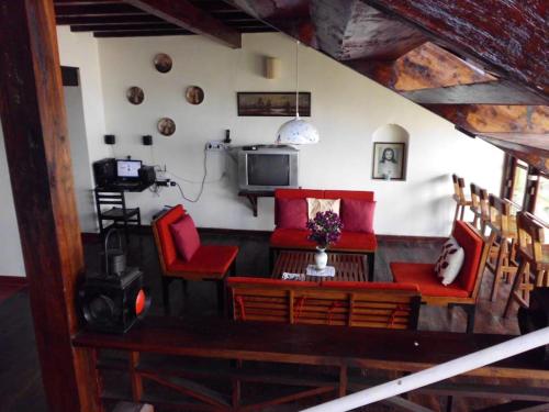 a living room with red chairs and a tv at WOODEN CHALET ON THE RIVER BANKS in Old Goa
