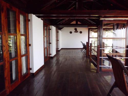 an empty room with wooden floors and glass doors at WOODEN CHALET ON THE RIVER BANKS in Old Goa