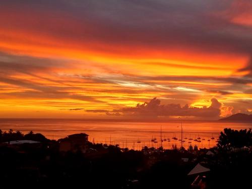 a sunset over the ocean with boats in the water at MARINA BLUE fabuleux Appartement vue LAGON in Punaauia